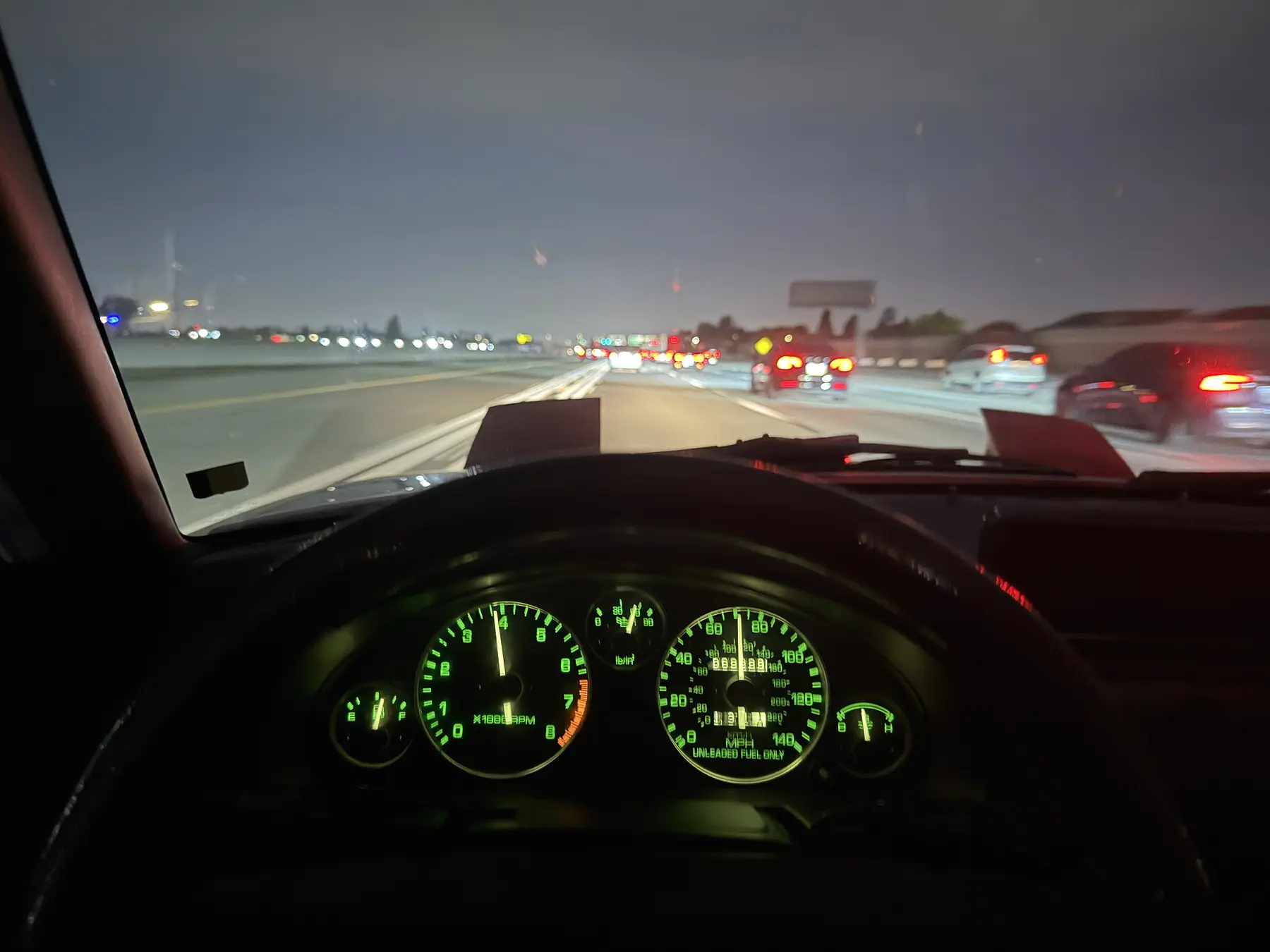 The Miata's illuminated gauges and the nighttime freeway ahead during the drive home